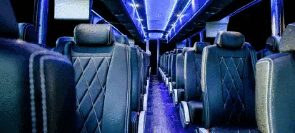 Coach bus interior with forward-facing seats and blue ceiling lighting