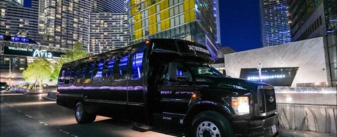 Black party bus outside city buildings at night